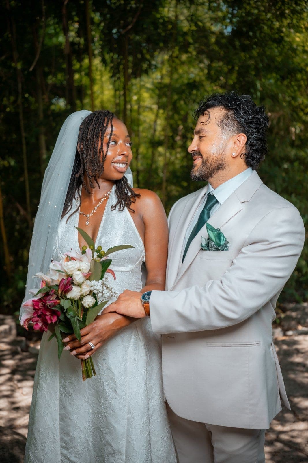 Bride holding a floral bouquet and groom smiling at each other during an outdoor wedding portrait in Austin, Texas.