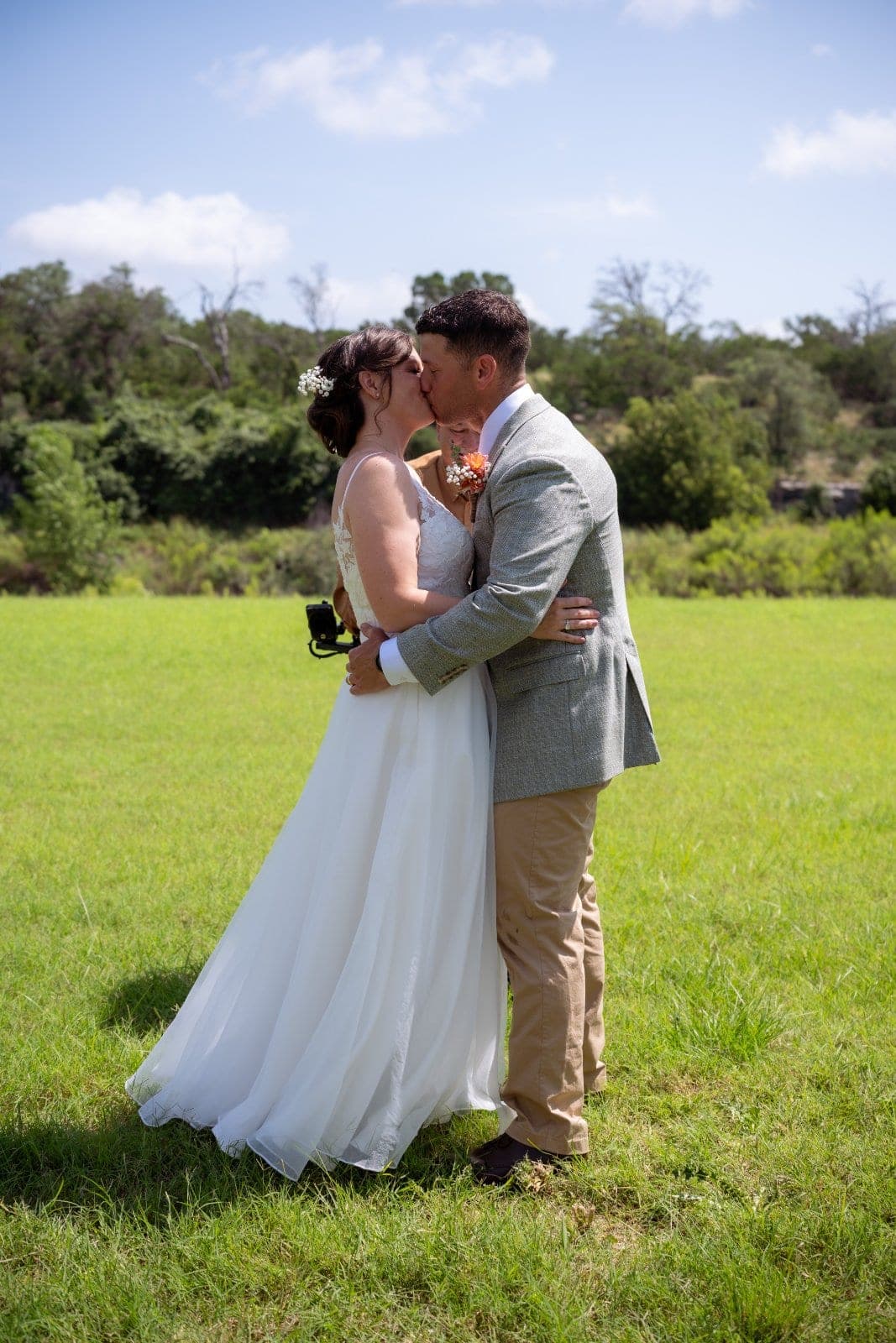Bride and groom sharing a romantic kiss in a sunny field during their Austin, Texas wedding.